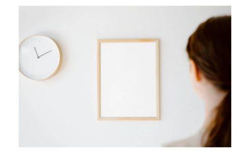 Una mujer de espaldas mirando un pared con un reloj