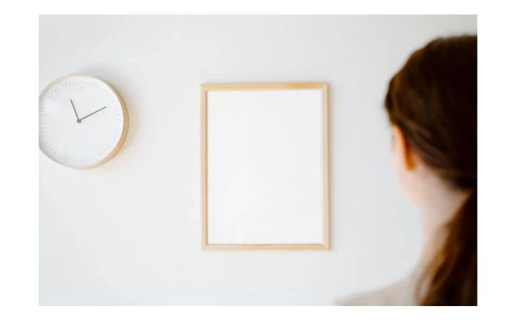 Una mujer de espaldas mirando un pared con un reloj