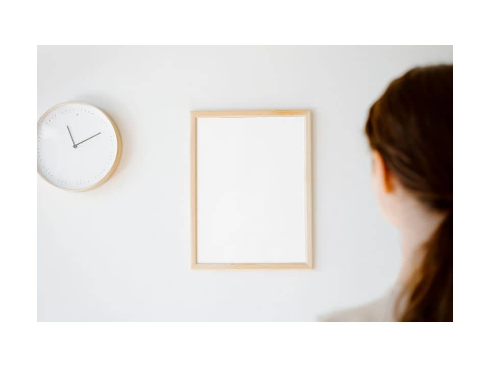 Una mujer de espaldas mirando un pared con un reloj